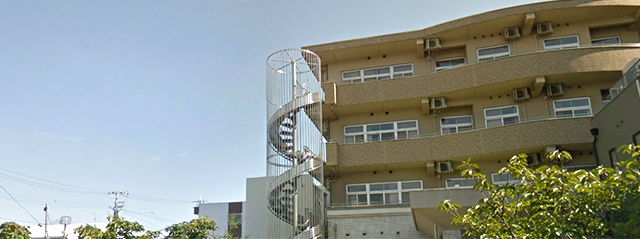 介護施設の外観。複数階の建物と螺旋階段が見える